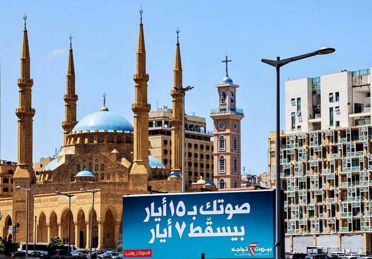 لوحة إعلانية: "تصويتك يوم 15 مايو سيلغي 7 مايو"، في إشارة إلى حادثة وقعت عام 2009 أمام مسجد محمد الأمين وكاتدرائية القديس جاورجيوس المارونية في ساحة الشهداء في بيروت