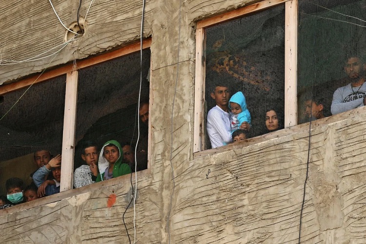 لاجئون سوريون ينظرون من نوافذ مبنى قيد الإنشاء يستخدمونه كمأوى في مدينة صيدا في جنوب لبنان
