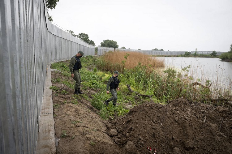 رجال الشرطة يقومون بدوريات بجانب جدار حديدي في نهر إفروس، بالقرب من قرية بوروس، على الحدود اليونانية التركية