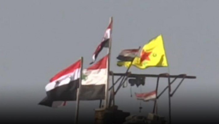 راية وحدات حماية الشعب مع العلم الرسمي السوري في أحد المواقع بسوريا