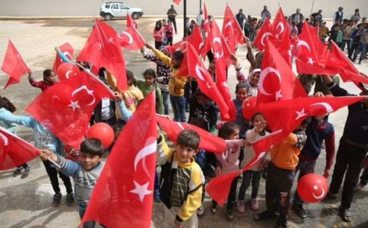 أطفال من قرى عفرين يحملون علم تركيا في ظل تغييب علم بلادهم سوريا